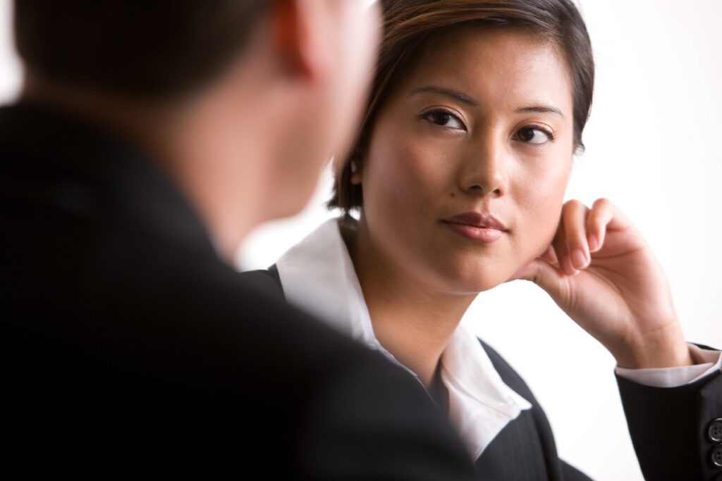 Woman leaning her face on her hand and listening to her co-worker